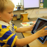child using an ipad at austin childrens academy
