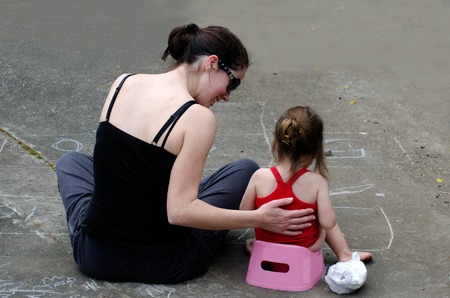 a young mother trains her daughter to use the potty outdoor