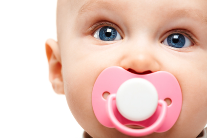 Face of adorable baby with pacifier in mouth looking at camera