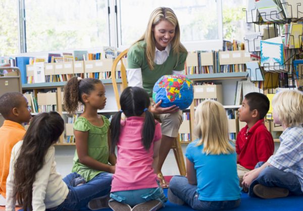 Kindergarten teacher and children looking at globe in a montessori