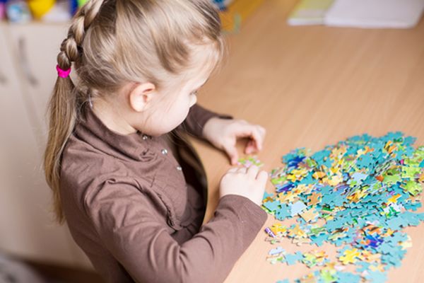 Cute little girl playing puzzles at the table