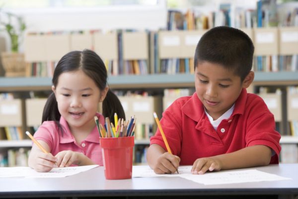 Kindergarten children sitting at desk and writing in classroom