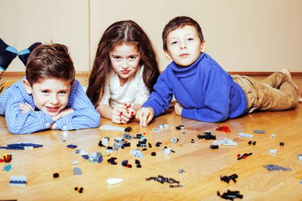 funny cute children playing lego at home, boys and girl smiling, first education role lifestyle