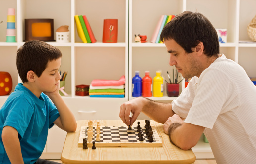 Child and adult playing game of chess